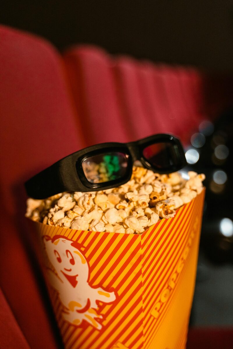 Close-up of popcorn and 3D glasses on cinema seats, ready for a movie experience.